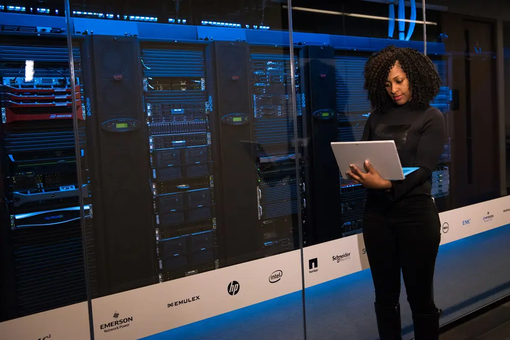 IT engineer with a laptop beside server racks